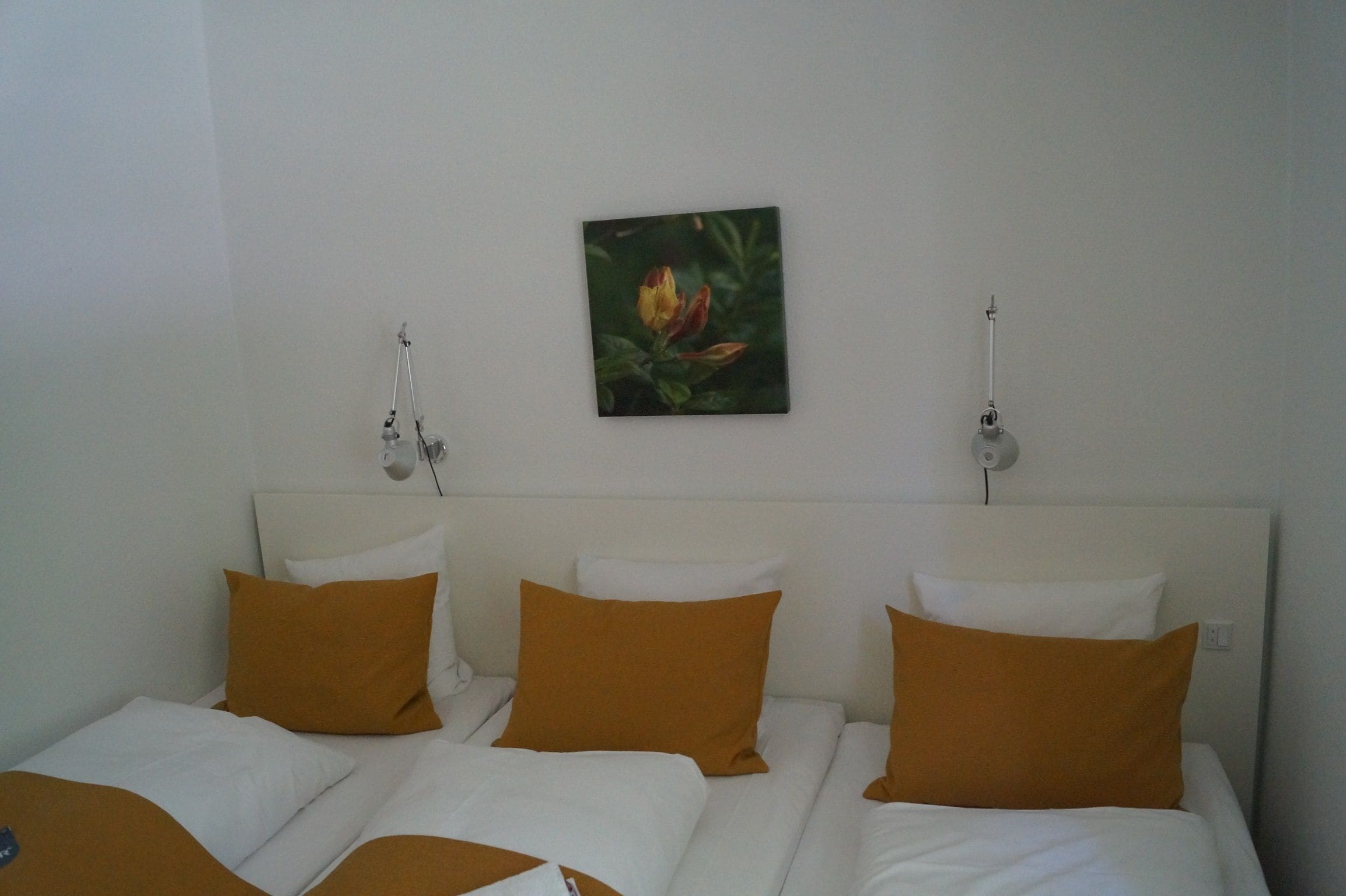 A hotel room with a bed, white bedding, and a single wall-mounted picture.