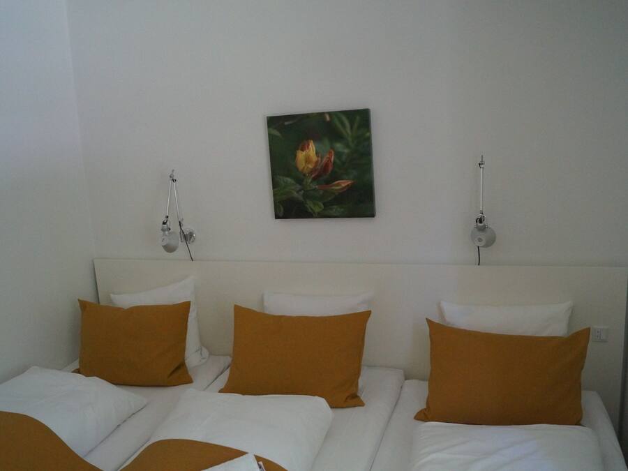 Una habitación de hotel con una cama, ropa de cama blanca y un cuadro colgado en la pared.