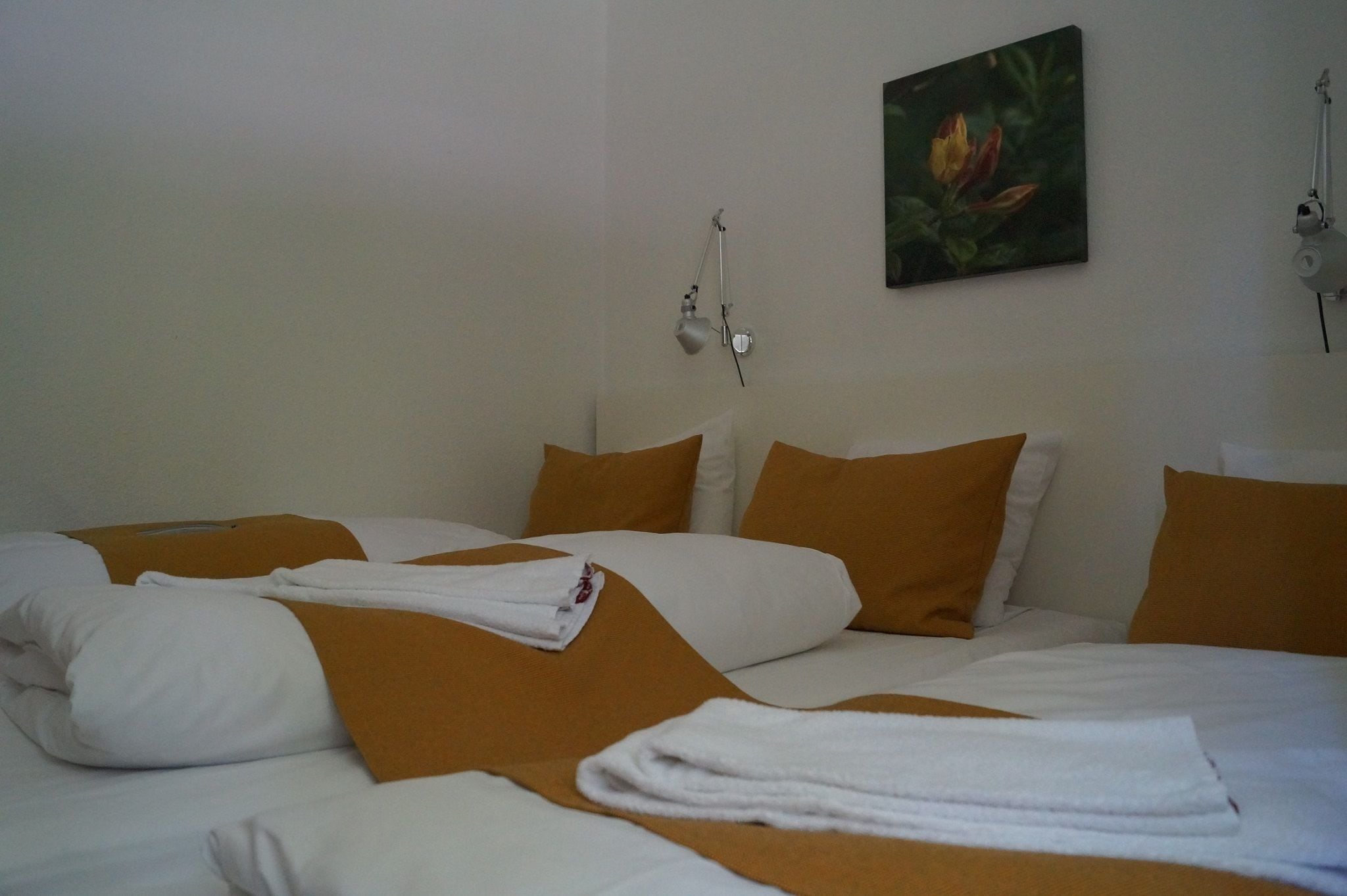 Una habitación de hotel con cama, ropa de cama blanca y marrón, un cuadro en la pared y una lámpara de escritorio.