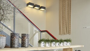 Una escalera moderna con barandilla de madera, plantas en macetas y un estante con objetos decorativos.
