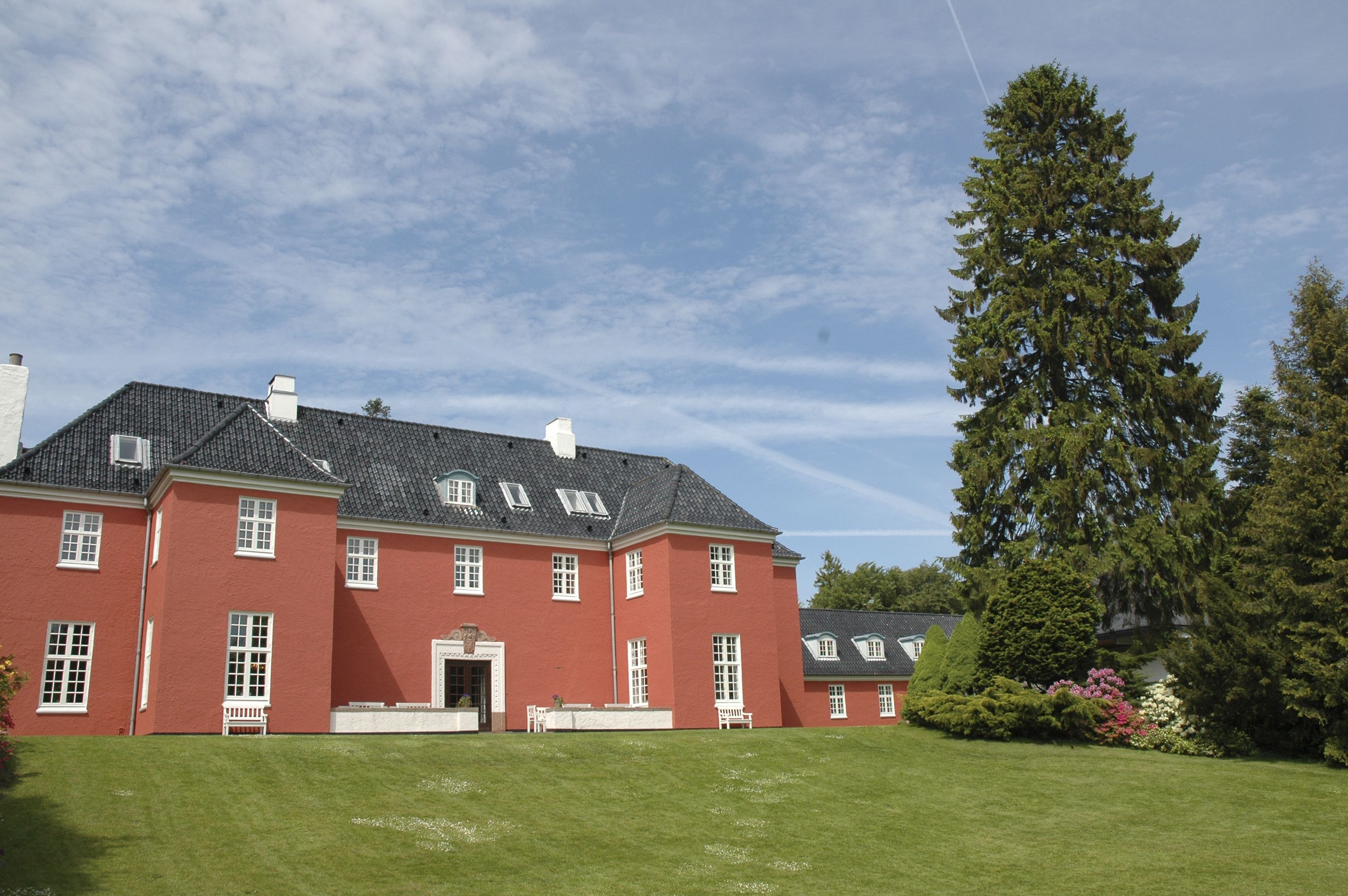 A large red building with multiple windows and a well-maintained lawn.