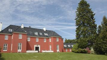 A large red building with multiple windows and a well-maintained lawn.
