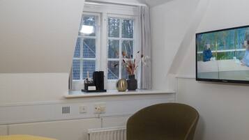 A room with a window, a radiator, a television, and a chair.