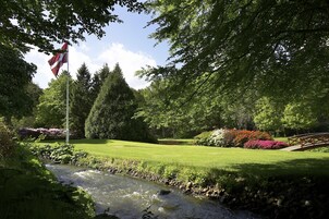 Un jardín tranquilo con una bandera, un arroyo y un puente.