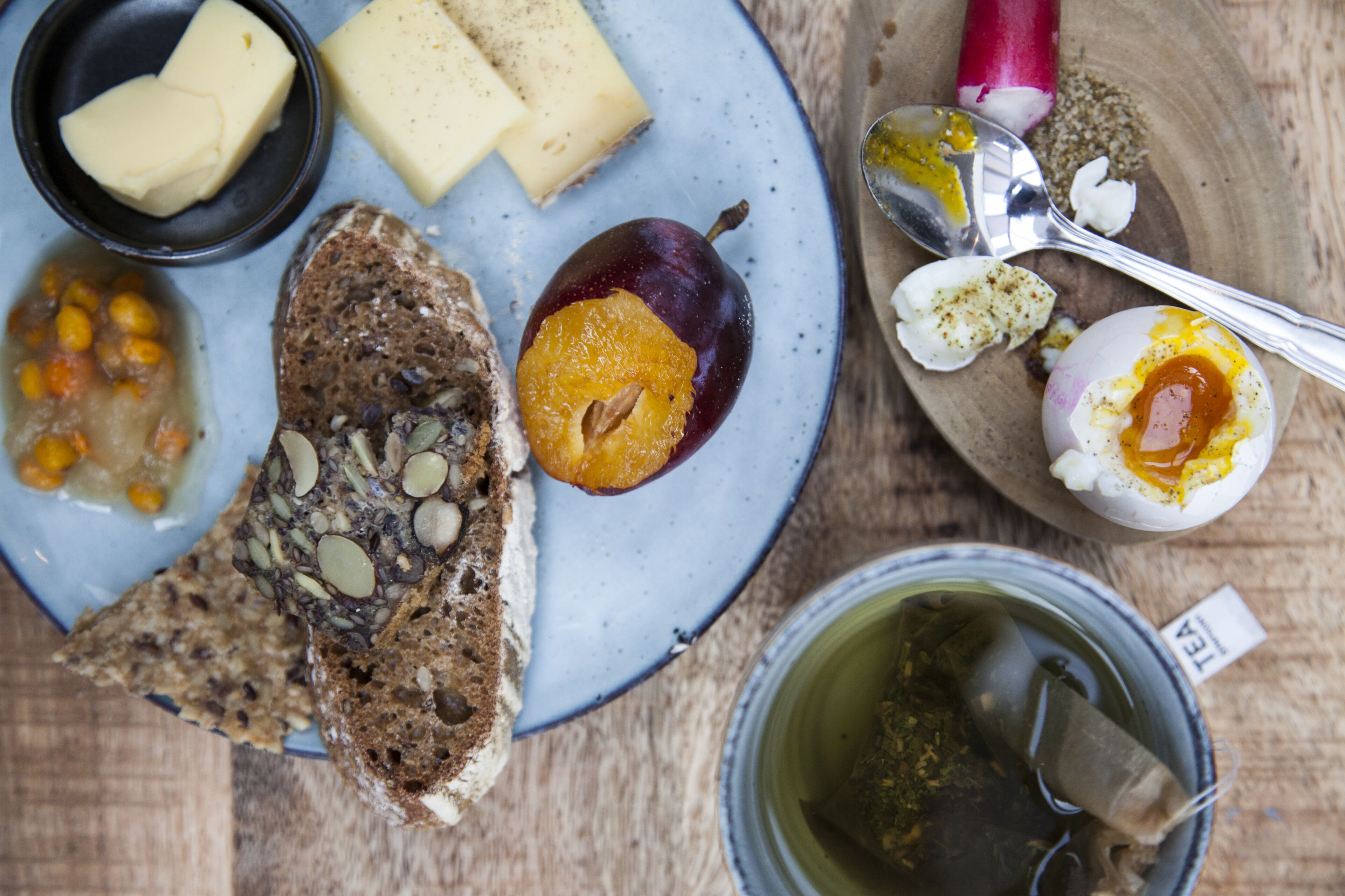A plate with various foods including cheese, a plum, and bread.