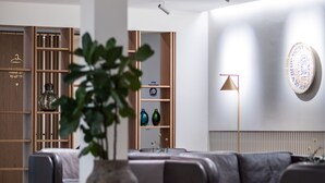 Una sala de estar moderna con un sofá, una planta grande en maceta y una lámpara de pie.