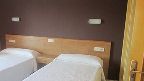 A room with two single beds, wooden headboards, and wall-mounted light switches. - Hotel Ronsel (Sanxenxo)