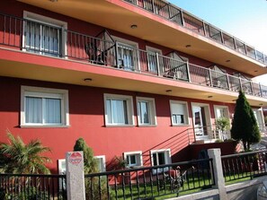 A red building with balconies, windows, and a sign. - Hotel Ronsel (Sanxenxo)