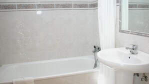 A bathroom with a bathtub, a sink, and a mirror. - Hotel Ronsel (Sanxenxo)
