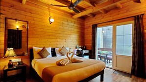 A wooden cabin room with a bed, a desk, and a large window. - La Vie Woods (Calangute)