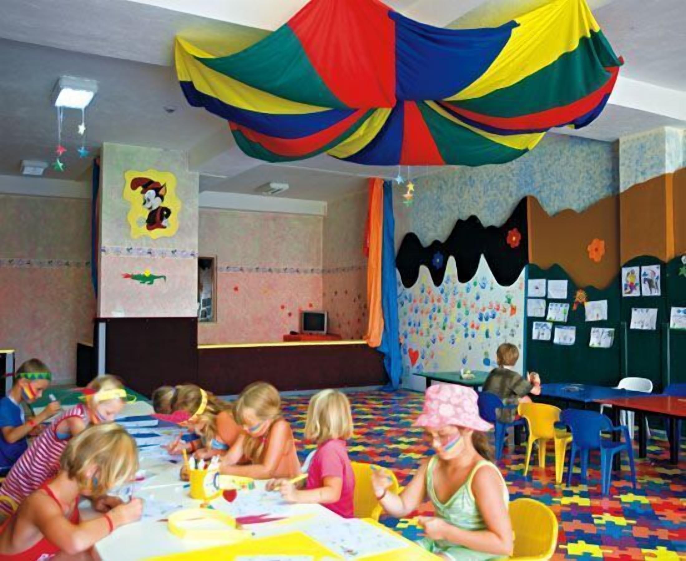 A classroom with children engaged in activities, colorful decorations, and educational posters on the walls.