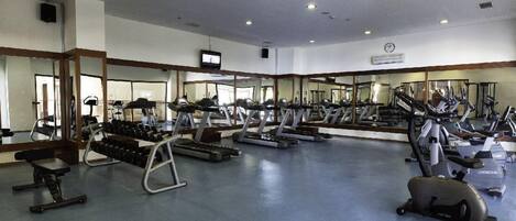 A gym with various exercise equipment, including treadmills, stationary bikes, and free weights.