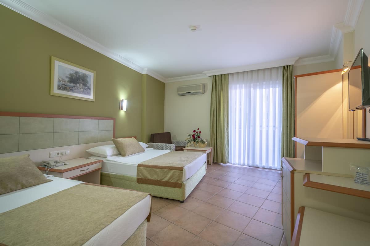 A hotel room with two beds, a desk, a chair, a TV, and a window with curtains.
