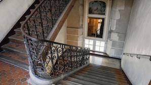 A spiral staircase with ornate metal railings and wooden steps. - MIJE Marais - Hostel (Paris)