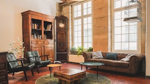 A cozy living room with a wooden cabinet, leather chairs, a sofa, and a coffee table. - MIJE Marais - Hostel (Paris)