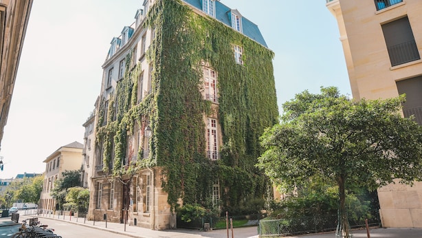 A building with a unique facade covered in ivy, featuring multiple windows and balconies. - MIJE Marais - Hostel (Paris)