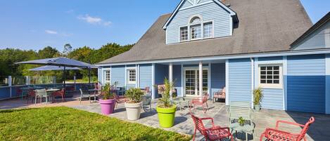 A blue house with a covered patio area featuring outdoor furniture and potted plants.