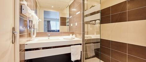 A modern bathroom with a glass shower enclosure, a white sink, and a large mirror.