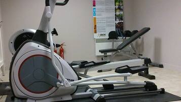 A gym with exercise equipment including an elliptical trainer, a treadmill, and a stationary bike.