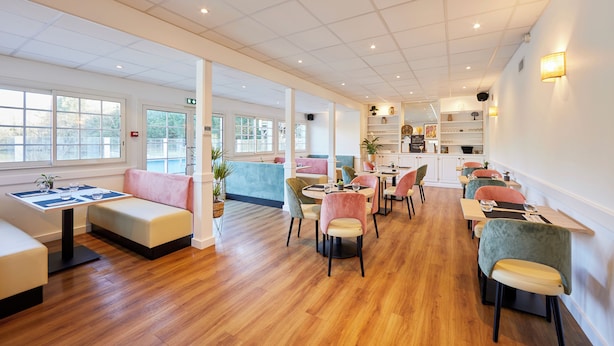 Un espace de restauration moderne avec un plancher en bois, des sièges rembourrés et une variété de chaises.