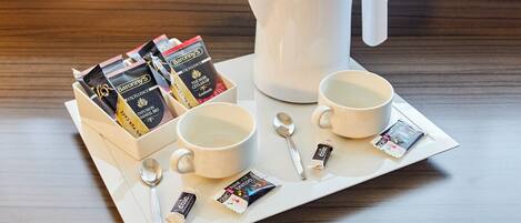 A tray with a white coffee pot, two white cups, a spoon, and several packets of Barony's tea.