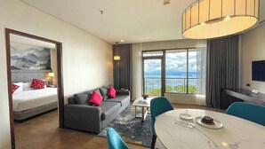 Una habitación de hotel con una cama, un sofá, una mesa de comedor y vista al océano.