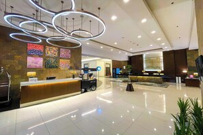 A modern hotel lobby with a reception desk, a coffee cart, and a seating area.