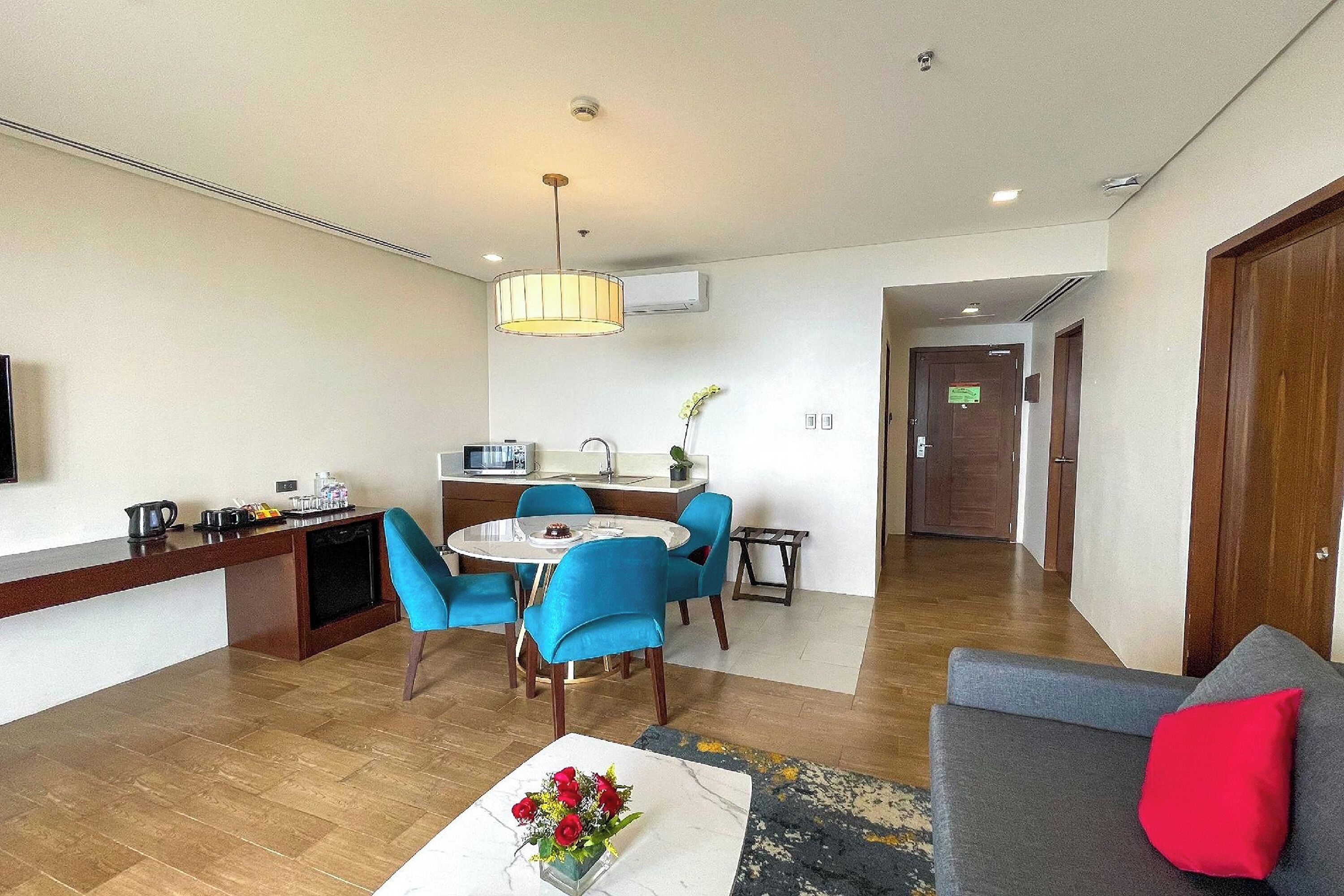 Une chambre d’hôtel moderne dotée d’un coin repas, d’un canapé et d’un espace dédié à la préparation du café.