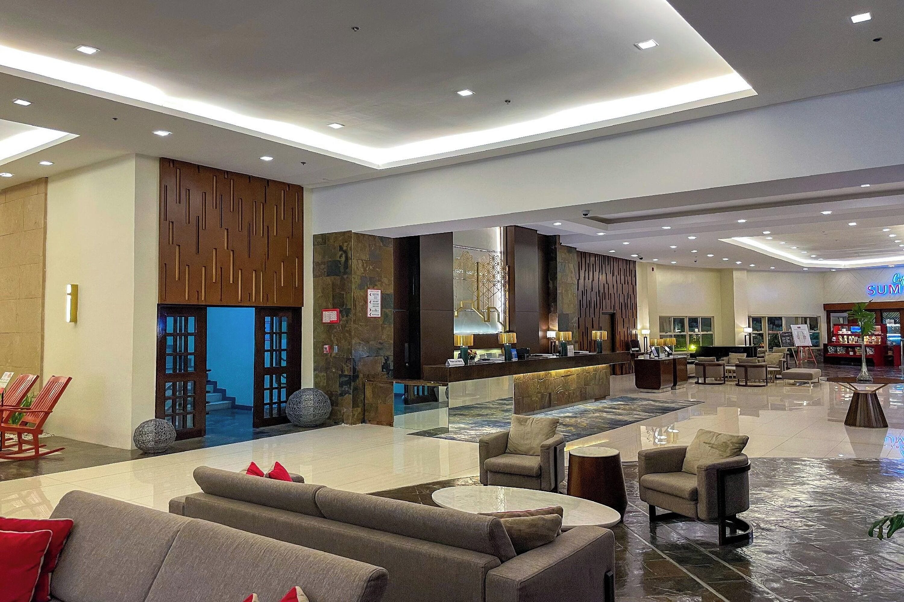 A spacious lobby with a reception desk, seating area, and a view of the outside.