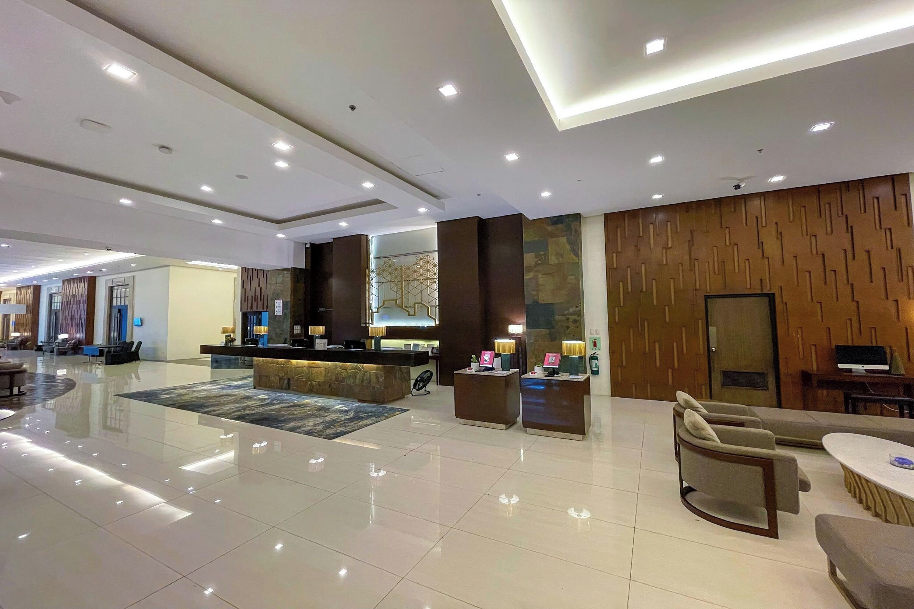 A spacious lobby with a reception desk, seating area, and a large mirror.