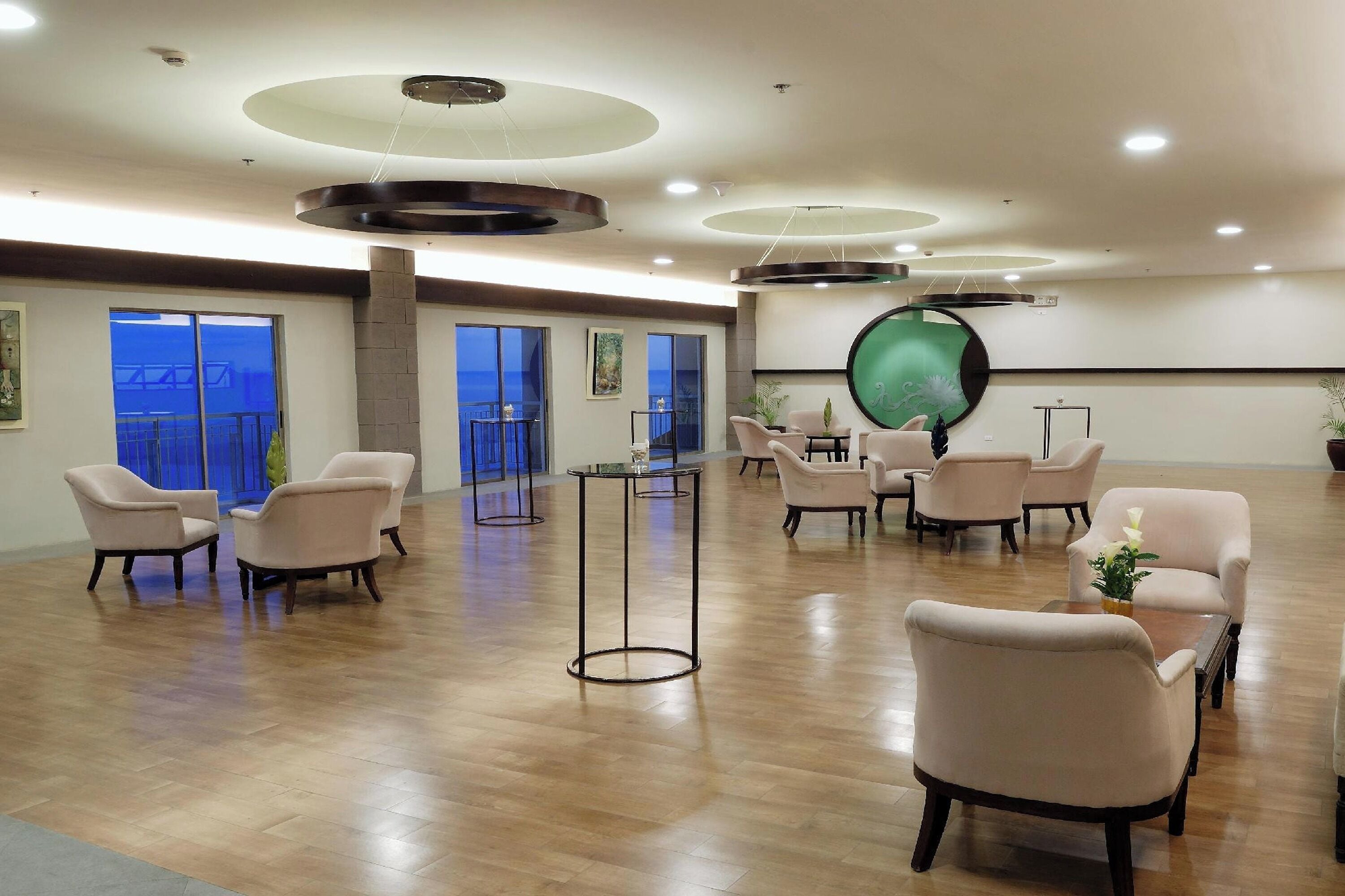 Una habitación amplia con varias zonas de estar, un gran ventanal circular y un diseño de techo moderno.