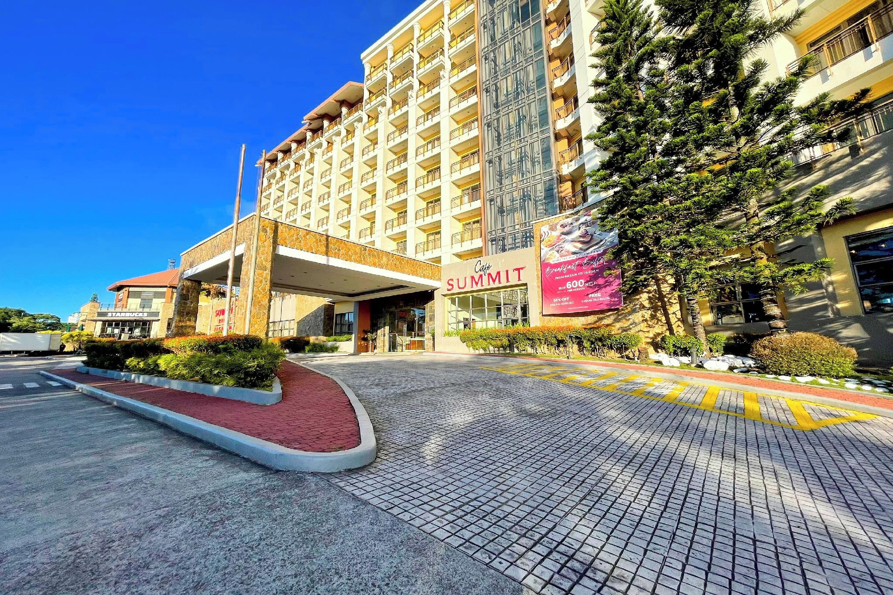 A hotel entrance with a red-brick pathway leading to a covered area, a Starbucks, and a large banner advertising a 600-room hotel.