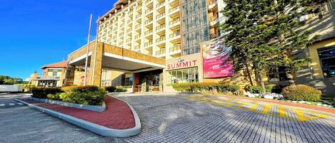 A hotel entrance with a red-brick pathway leading to a covered area, a Starbucks, and a large banner advertising a 600-room hotel.