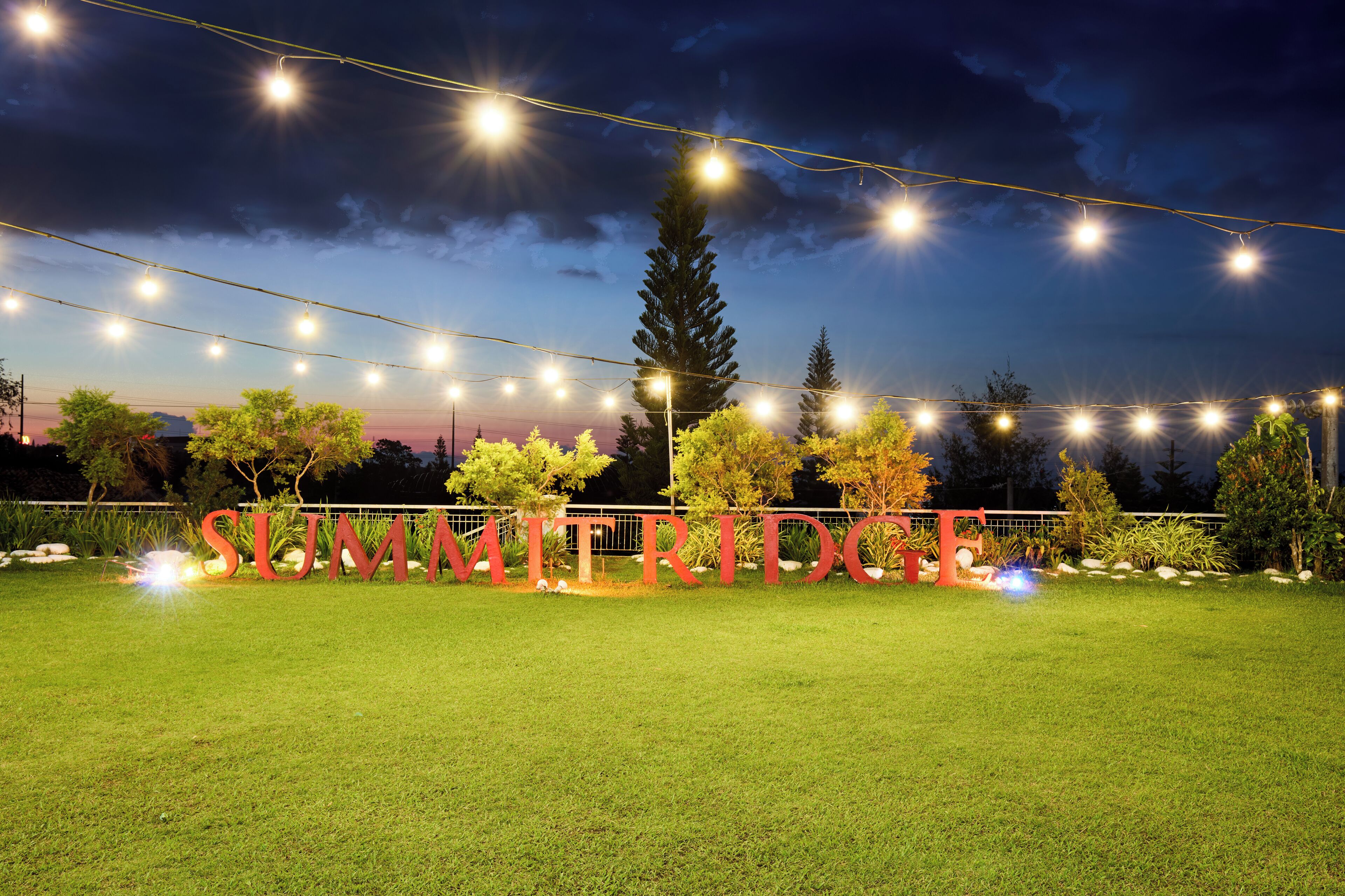 A well-lit outdoor area with a sign reading "SUMMIT RIDGE" and string lights overhead.