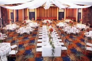 Un salón de banquetes con mesas redondas, manteles blancos y sillas.