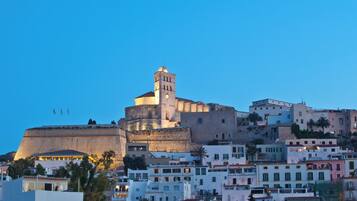 Un bâtiment fortifié d’importance historique, doté d’une tour imposante, entouré d’immeubles résidentiels aux balcons et terrasses.