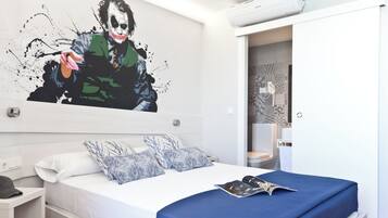 A modern hotel room with a large bed, a nightstand, a wall-mounted air conditioner, and a bathroom visible through an open door.