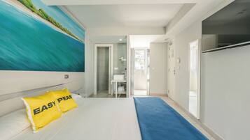 Ein Hotelzimmer mit Bett, einem Strandbild, einem Badezimmer und Blick auf die Stadt.