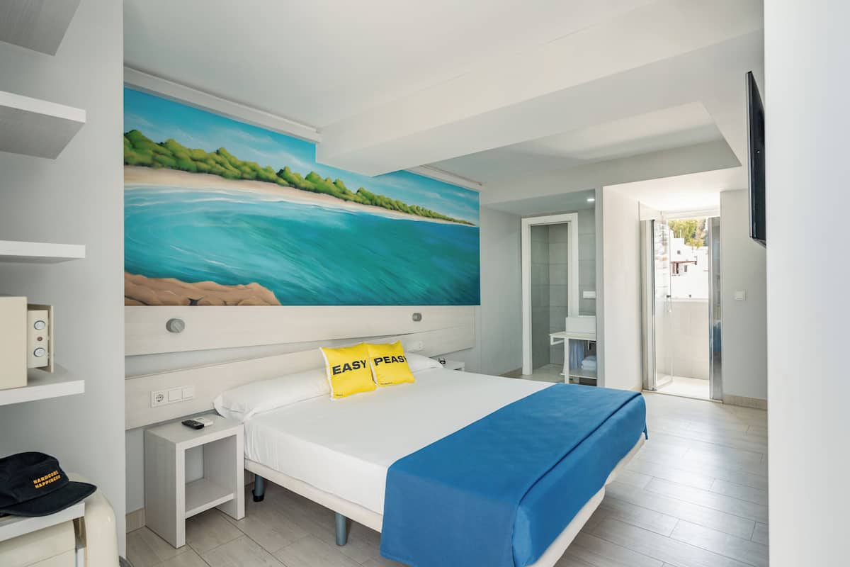 Ein modernes Schlafzimmer mit einem großen Bett, einem Bild von einer Strandansicht und einer blauen Decke.