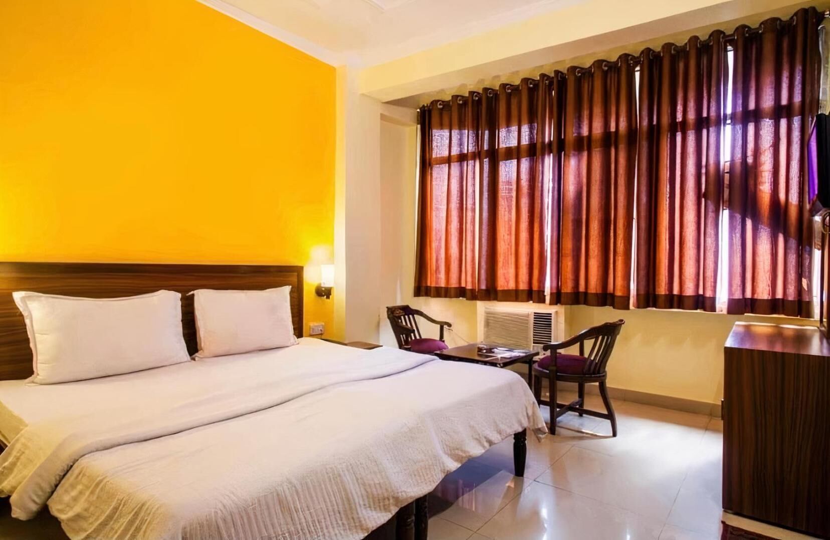 Una habitación de hotel con una cama grande, un escritorio con una silla y una ventana con cortinas.
