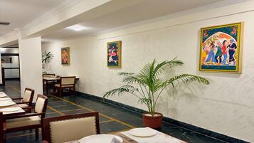 Un restaurante con suelos de mármol, sillas de madera, mesas dispuestas con platos y cubiertos, y decoración en las paredes.