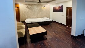 A modern room with a bed, a sofa, a small table, a ceiling fan, and a wall-mounted artwork. - Hotel Himalaya Haridwar @ Har Ki Pauri Road (Haridwar)