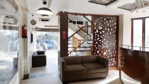 Eine moderne Lobby mit einem braunen Sofa, einer Treppe und einem dekorativen Raumteiler.