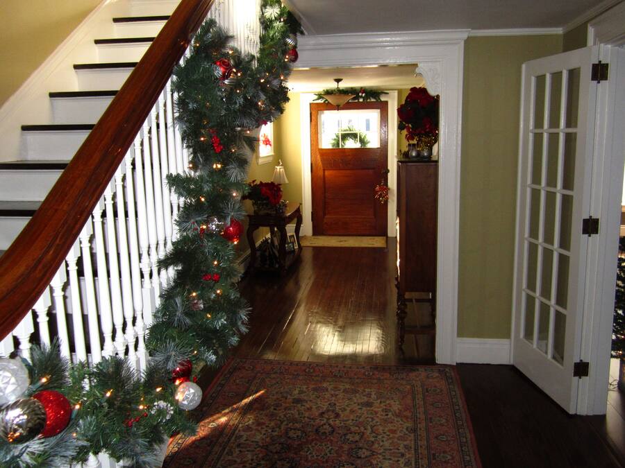 A staircase with a Christmas garland, a patterned rug, and a wooden door at the end.
