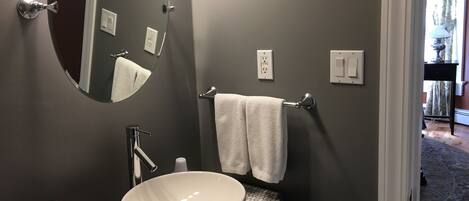 Un bagno moderno con uno specchio rotondo, un lavabo a incasso e un porta asciugamani.