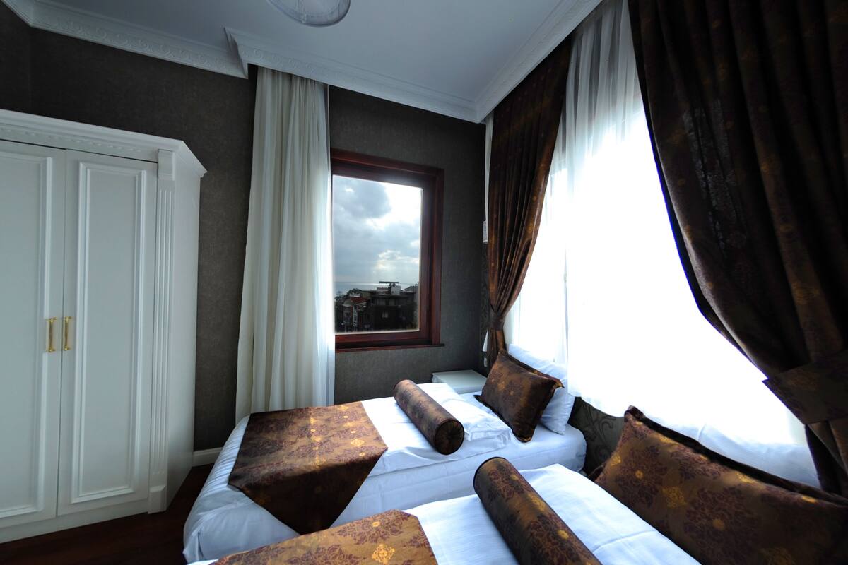 Una habitación de hotel con una cama grande, un armario y una ventana con cortinas.