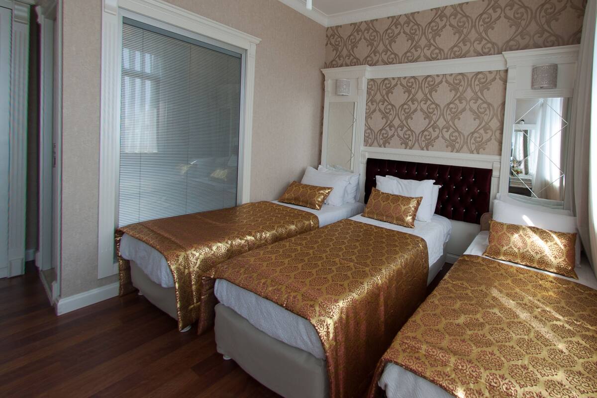 Habitación de hotel con dos camas, un espejo grande y un papel tapiz estampado.