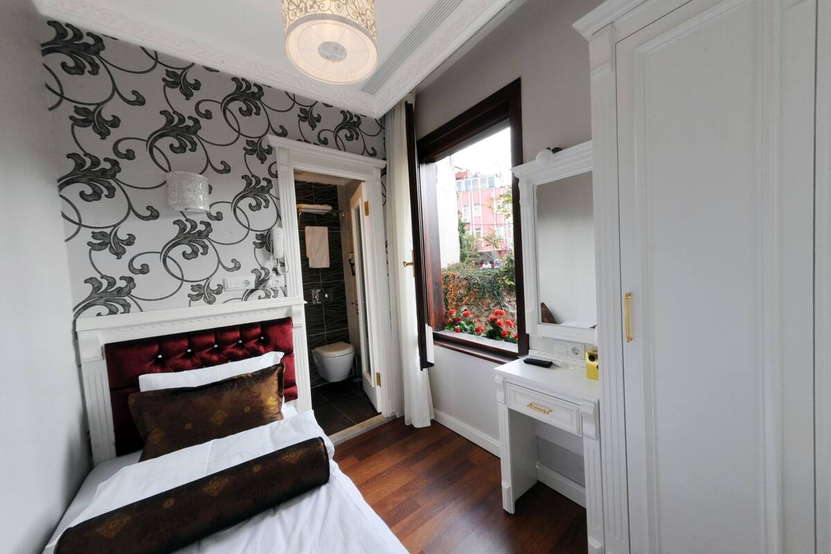 Un dormitorio con cama, escritorio, ventana con vistas y baño.
