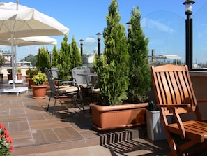 Eine Terrasse mit Sitzgelegenheit im Freien, Blumentöpfen und Blick auf die Stadtlandschaft.