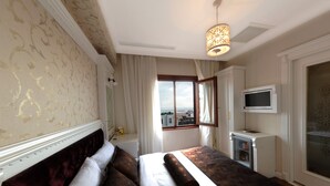 Habitació d'hotel amb un llit gran, televisió i finestra amb vistes.